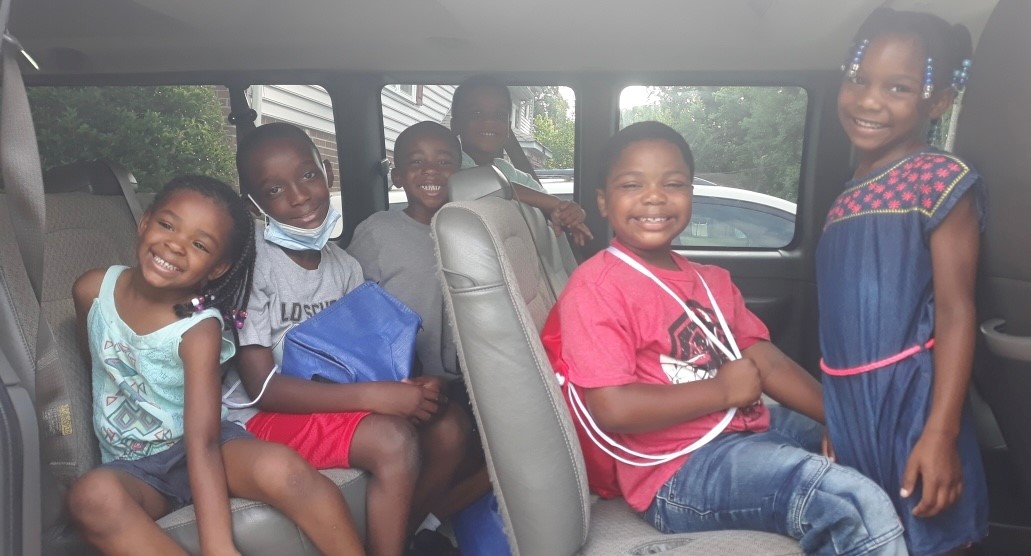 Children smiling in a van on the way to camp