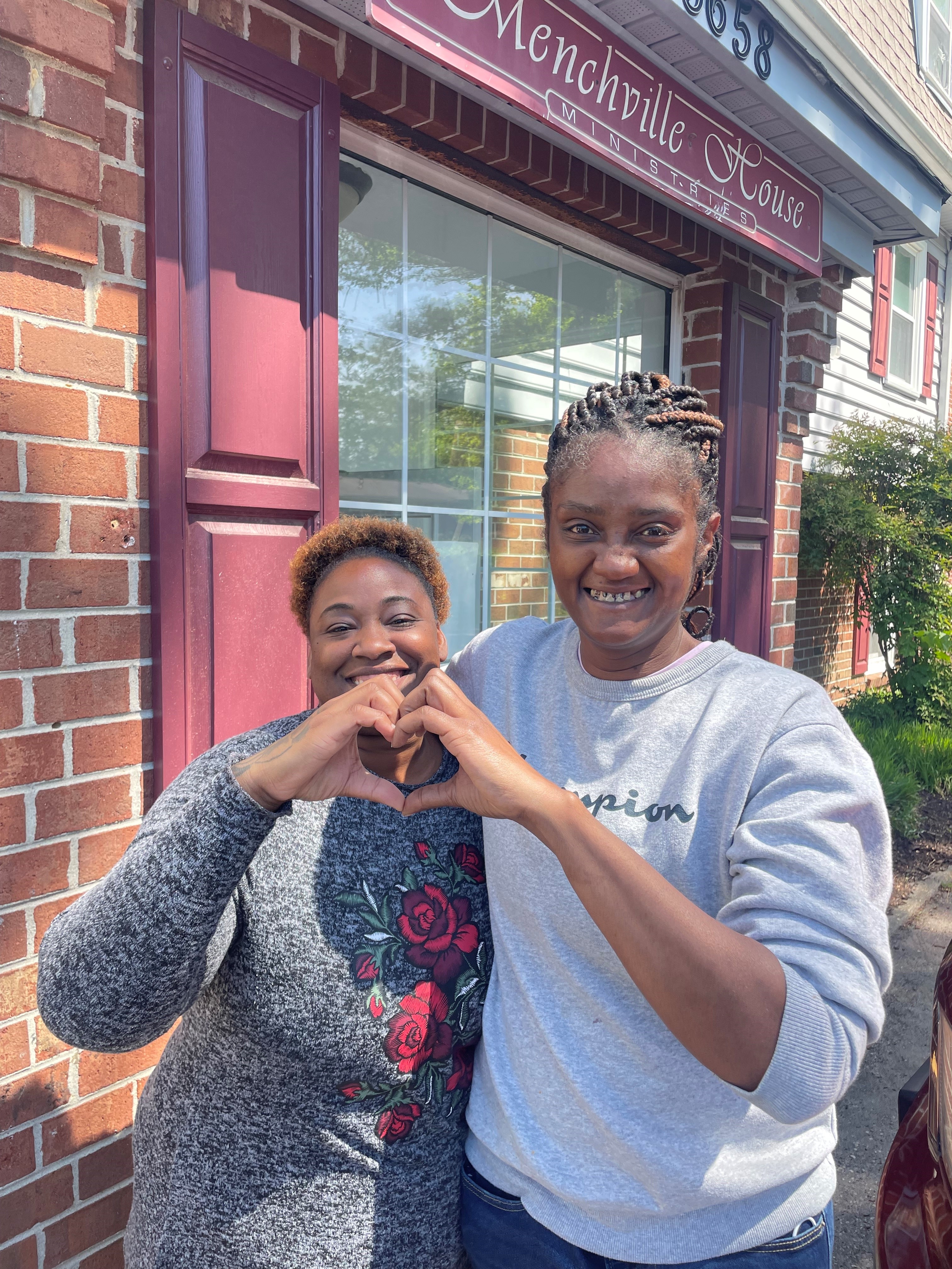 Families making a heart shape in front of Menchville House